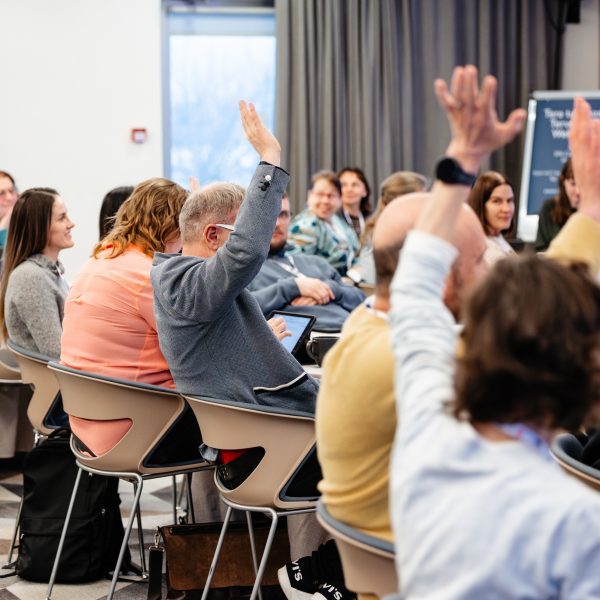 Rahvusvahelisel haridusüritusel konverentsiruumis toimuv interaktiivne arutelu, kus osalejad tõstavad käe.