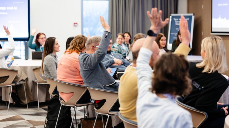 Rahvusvahelisel haridusüritusel konverentsiruumis toimuv interaktiivne arutelu, kus osalejad tõstavad käe.